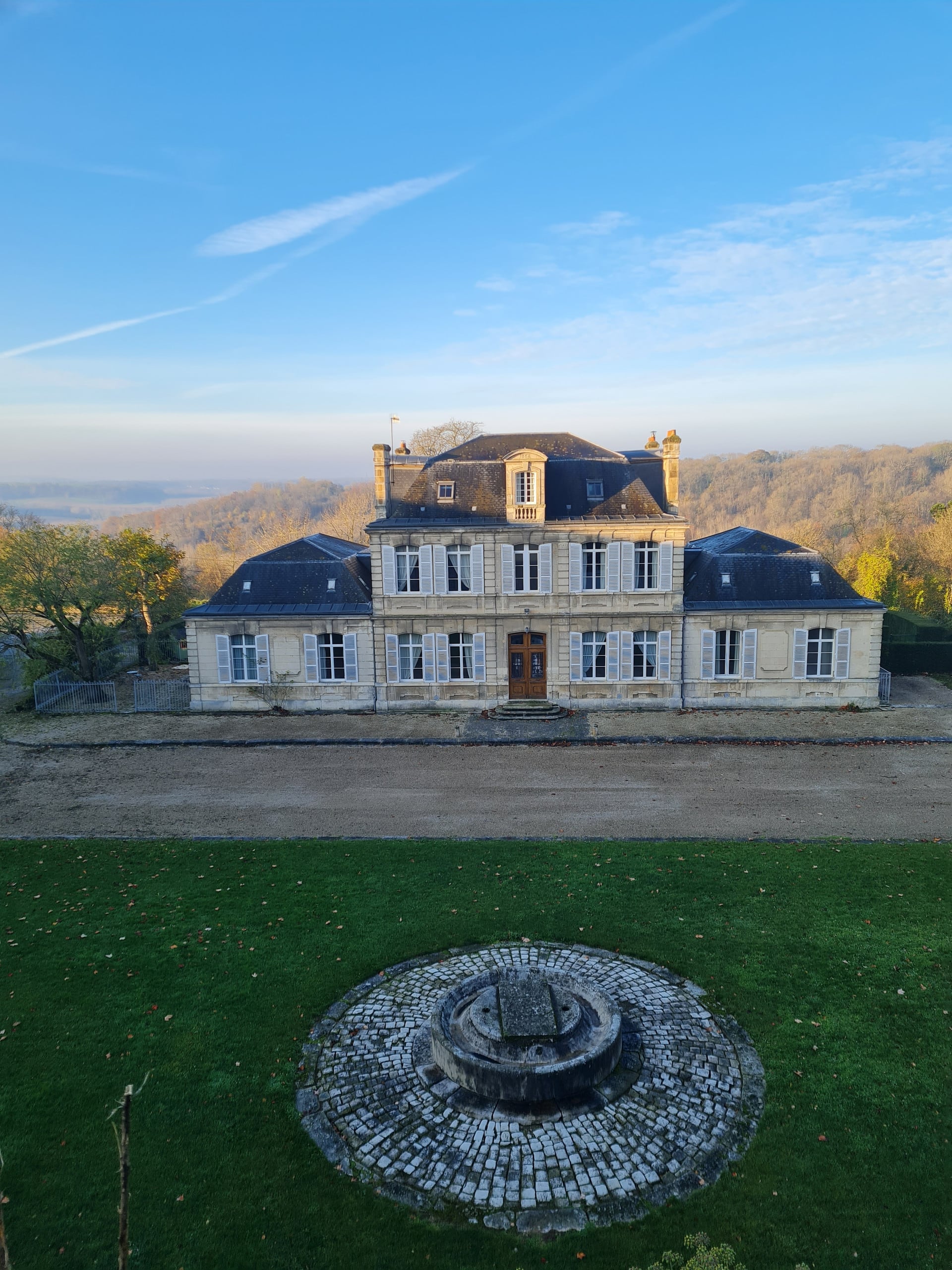 Façade du grand gîte La Carrière l'Évêque, demeure de caractère en pierre de taille, vue aérienne avec fontaine en pavés